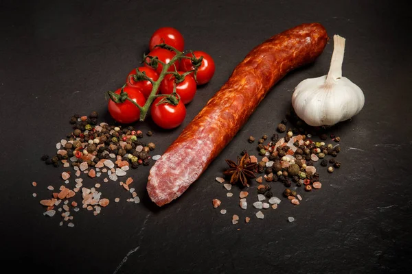 Вид зверху довгий шматочок копченої сухої ковбаси з часником і помідорами — стокове фото