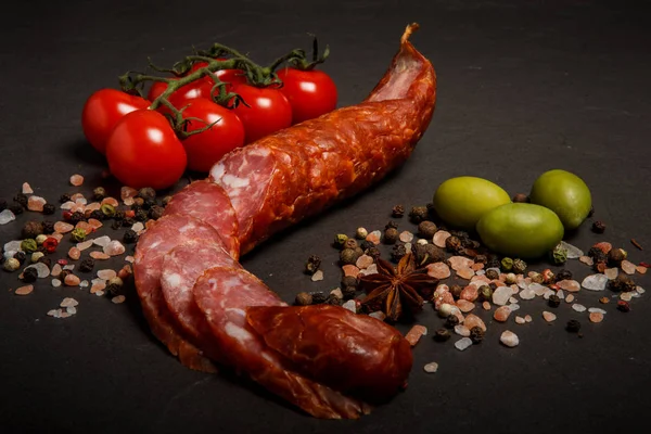 Delicatessen smoked dry cured sausage with olives and tomatoes — Stock Photo, Image