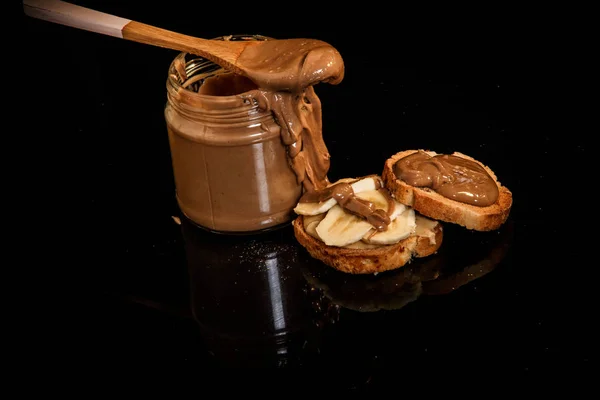 Top view on creamy peanut butter in glass jar and on crackers — Stock Photo, Image