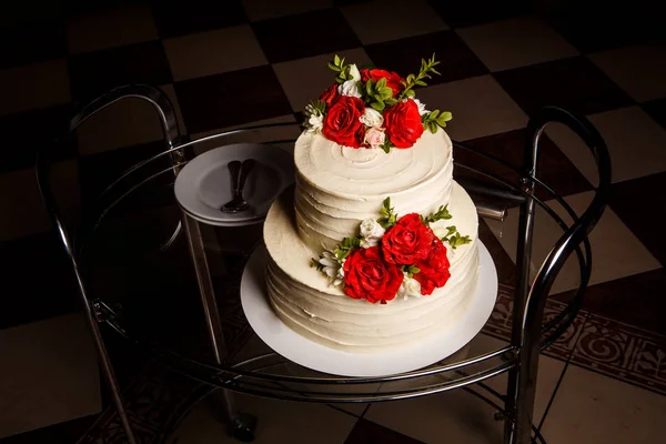 tasty wedding cake on glass tray with plates and spoons