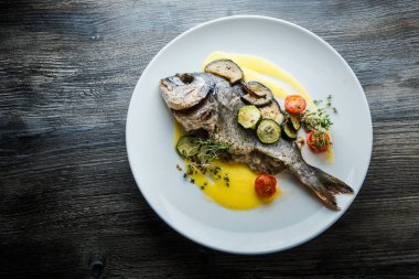 dilimlenmiş sebzelerle servis edilen lezzetli kızarmış balık ların üst görünümü
