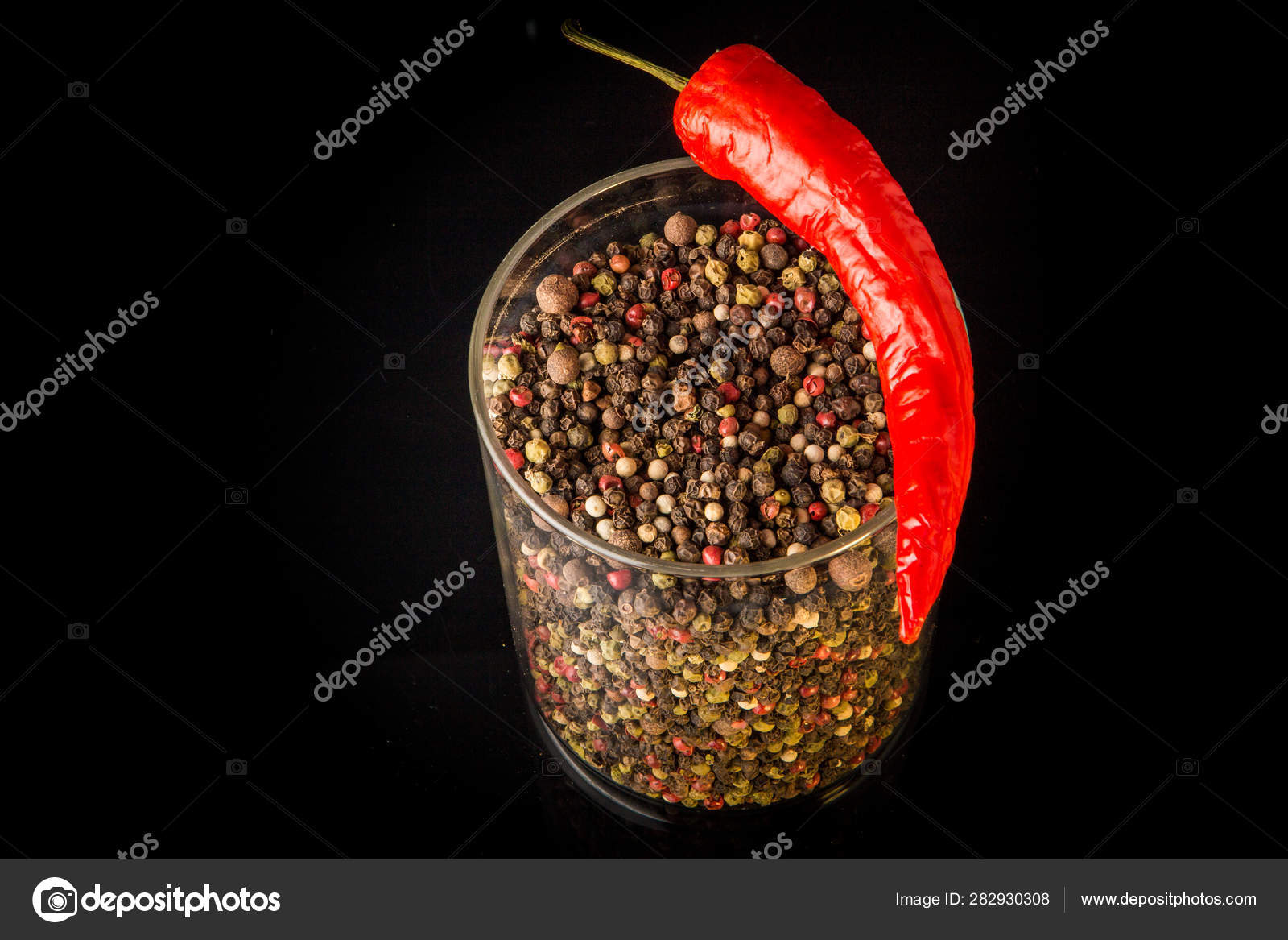 Top view of glass jar with peppercorns and one chili pepper Stock Photo