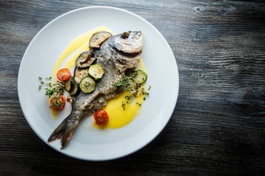 dilimlenmiş pişmiş sebze ile servis edilen kızarmış balık üst görünümü