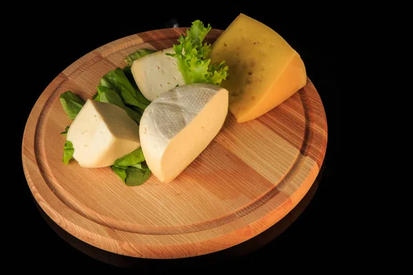 Вид сверху на сортированный твердый сыр на круглой деревянной доске — стоковое фото