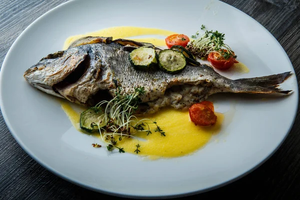 Вкусная рыба крупным планом подается с нарезанными овощами — стоковое фото