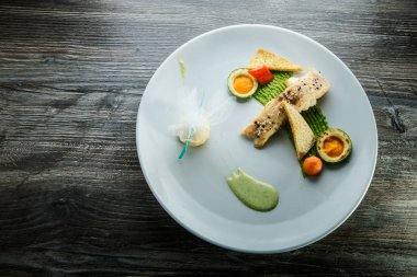 garnitür ile süslenmiş pişmiş beyaz balık parçası üzerinde üst görünümü