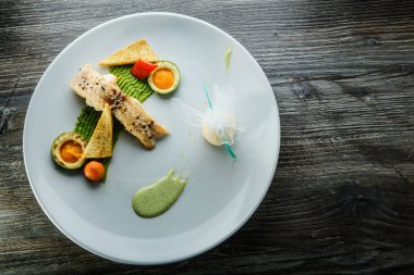 avokado ve püresi ile ince dekore edilmiş pişmiş beyaz balık parçası