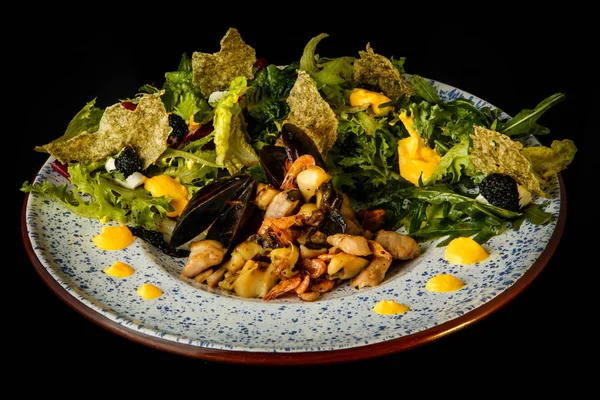 finely decorated restaurant appetizer of assorted seafood and salad leaves