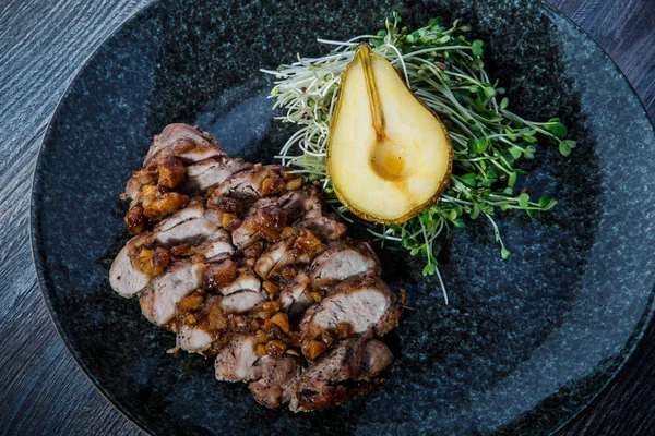 Top view closeup grilled meat slices with half of baked pear — Stock Photo, Image