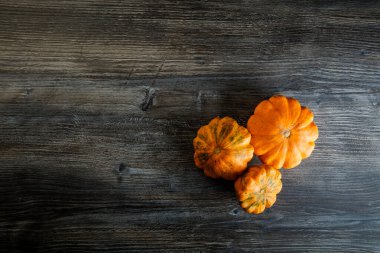 Tahta masada üç dekoratif sarı balkabağı.
