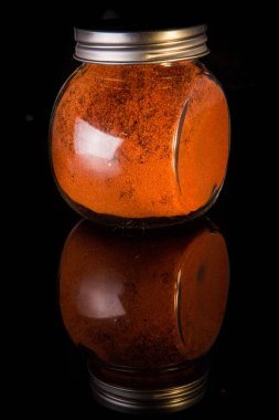 Yuvarlak cam kavanozda kırmızı kırmızı biber ve metal kaplama.