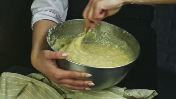 Primo piano donna tiene in mano grande ciotola di metallo con pasta morbida e mescolandolo con cucchiaio — Video Stock