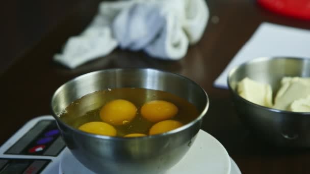 Closeup chef hands breaking up raw egg into metal bowl standing on scales — Stock Video