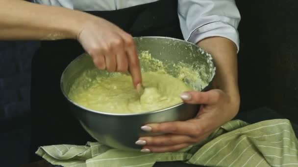 Primo piano donna tiene in mano ciotola di metallo con pasta morbida mescolando lentamente con cucchiaio — Video Stock