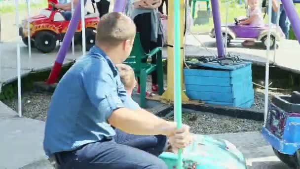 Veel kinderen rijden op verschillende auto 's en paarden op carrousel in park van attracties — Stockvideo