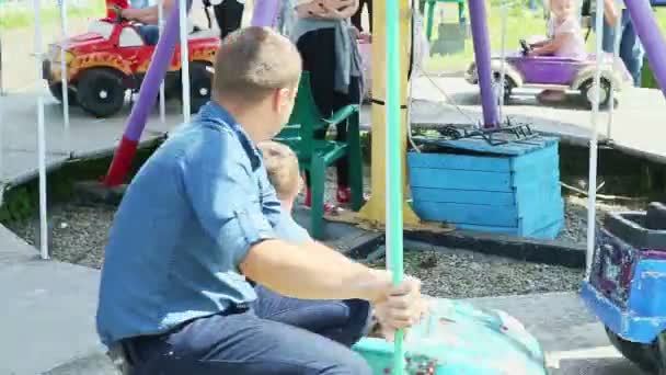 Viele Kinder, die auf verschiedenen Autos und Pferden auf einem Karussell im Park der Attraktionen reiten — Stockvideo