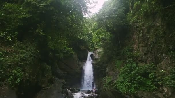 Lentamente panorama abajo en muchas personas diferentes que descansan cerca de una fuerte cascada — Vídeos de Stock