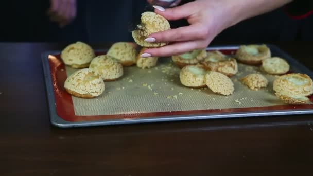 Gros plan mains féminines coupées au couteau biscuits à la crème choux et mettre sur palette à pâtisserie — Video