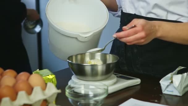 Konfektyr i kock uniform sätter socker av stor sked i färskt skivat smör — Stockvideo