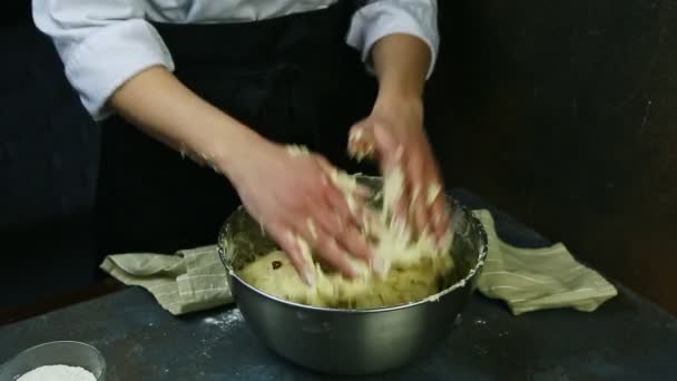 Osoba v kuchařské uniformě rychle hnětá měkké těsto s rozinkami ve velké hluboké kovové míse — Stock video