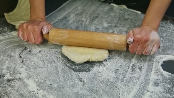 Крупным планом женские руки медленно выкатывают белое дрожжевое тесто деревянной скалкой — стоковое видео