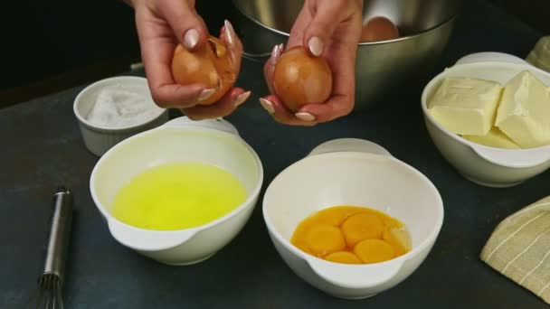 Primo piano mani pasticciere rompendo due uova crude tuorlo separato da proteine — Video Stock