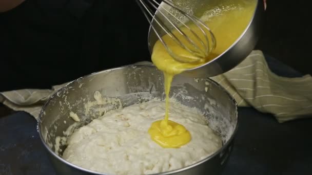 Zbliżenie kobieta ręce wlać whisked żółtka jaj do metalowej misce z ciasta drożdżowego — Wideo stockowe