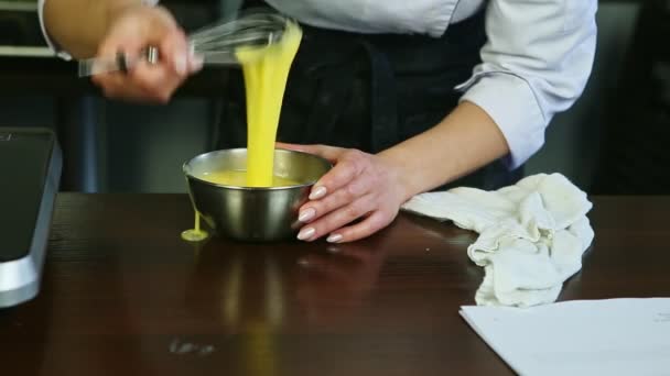 Detailní cukrářské ruce tím, že whisk míchání syrových vaječných žloutků s cukrem v kovové misce — Stock video