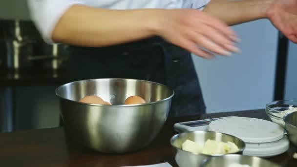 Primo piano donna in uniforme chef da mani mettendo uova crude in ciotola di metallo profondo — Video Stock