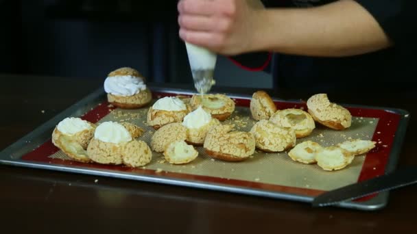 Крупним планом жіночі руки наповнюють заварне печиво чу кондитерським мішком з білим кремом — стокове відео