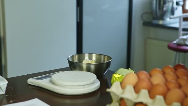 Μικρές λευκές ζυγαριές κουζίνας, μεταλλικό μπολ με βούτυρο και πολλοί δίσκοι με αυγά — Αρχείο Βίντεο