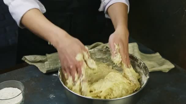 穿着厨师制服的妇女用手把软酵母面团迅速揉碎在金属碗里 — 图库视频影像