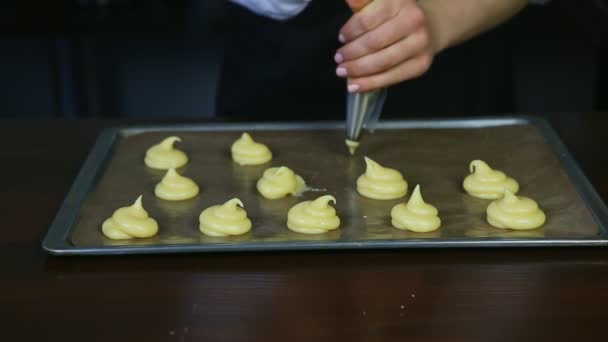 Konfektyr händer bildar vaniljsås kakor choux av bakverk påse på bakning pall — Stockvideo