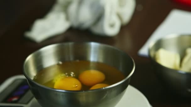Closeup woman hands breaking up raw egg into metal bowl standing on scales — Stock Video