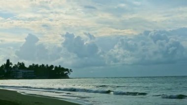 Pofuduk bulutların üzerinde yavaşça süzülür durgun mavi denizin üzerinde beyaz dalgalarla