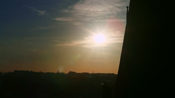 Fluffy clouds slowly flow above bright sun and old town silhouette on sunset — Stock Video