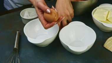 Yavaşça yaklaşan kadın, sarısını proteinden ayıran yumurtaları elleriyle kırıyor.