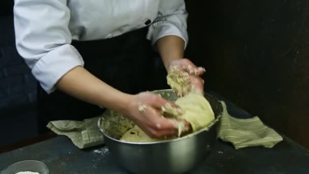 Žena v kuchařské uniformě rychle hnětá měkké těsto s rozinkami ve velké hluboké kovové míse — Stock video