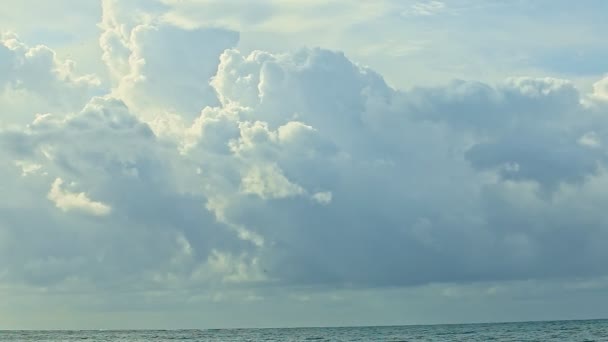 Медленно панорама, оставленная на ярком солнце, скрывающемся за белыми облаками над голубым океаном — стоковое видео