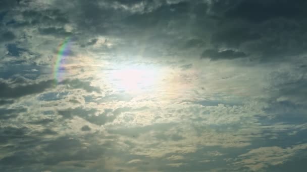 Heldere zon verbergen achter pluizige witte wolken waardoor regenboog effect — Stockvideo