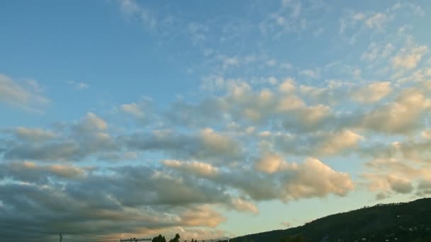 Pomalu panorama vpravo na nadýchaných mracích plují na západě slunce obloha nad nízkými tmavými horami — Stock video