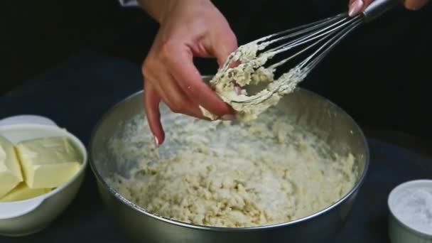 Slow motion närbild av kvinnliga händer rena rester av mjuk deg från visp — Stockvideo