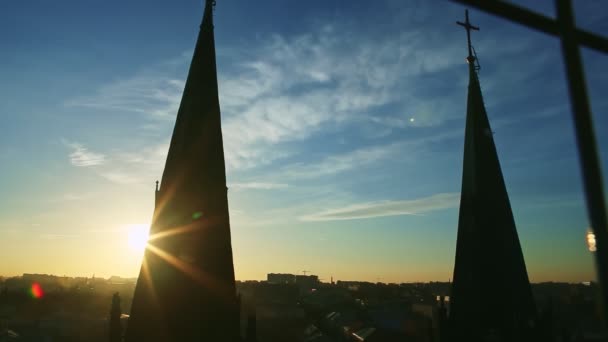 Yüksek kilise siluetlerinin arkasına saklanan parlak güneş, mavi günbatımı gökyüzüne karşı yükseliyor. — Stok video