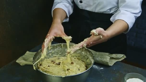 El confitero de cámara lenta limpia las manos de las sobras de masa por encima de un recipiente de metal — Vídeos de Stock