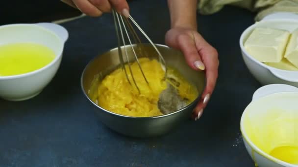 Slow motion closeup vrouwelijke handen door het mengen van eigeel met suiker in metalen kom — Stockvideo