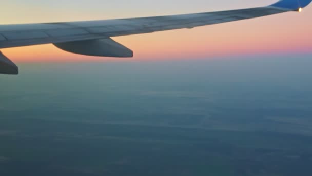 Soft focus luchtfoto op vliegtuig vleugel boven blauw land en witte mist tegen roze lucht — Stockvideo