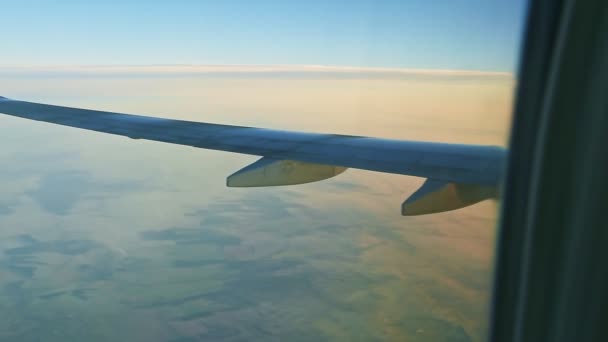 Luftaufnahme des Flugzeugflügels aus dem Fenster mit grünem Land und weißen Wolken — Stockvideo