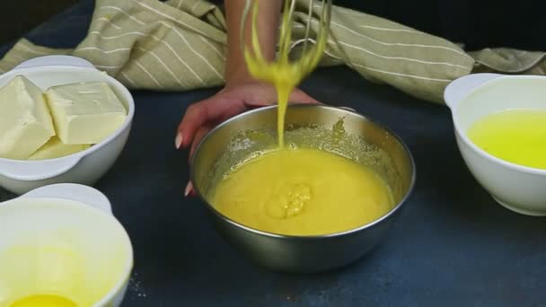Крупным планом женские руки взбивают медленно смешивая яичные желтки с сахаром в металлической миске — стоковое видео