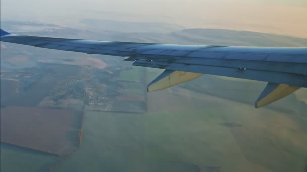 Vista aérea desde la ventana en el ala del avión volar por encima de las montañas y nubes blancas — Vídeos de Stock