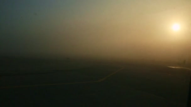 Panorámás kilátás a repülőgép ablakából a fényes napon keresztül sűrű köd napkeltekor — Stock videók